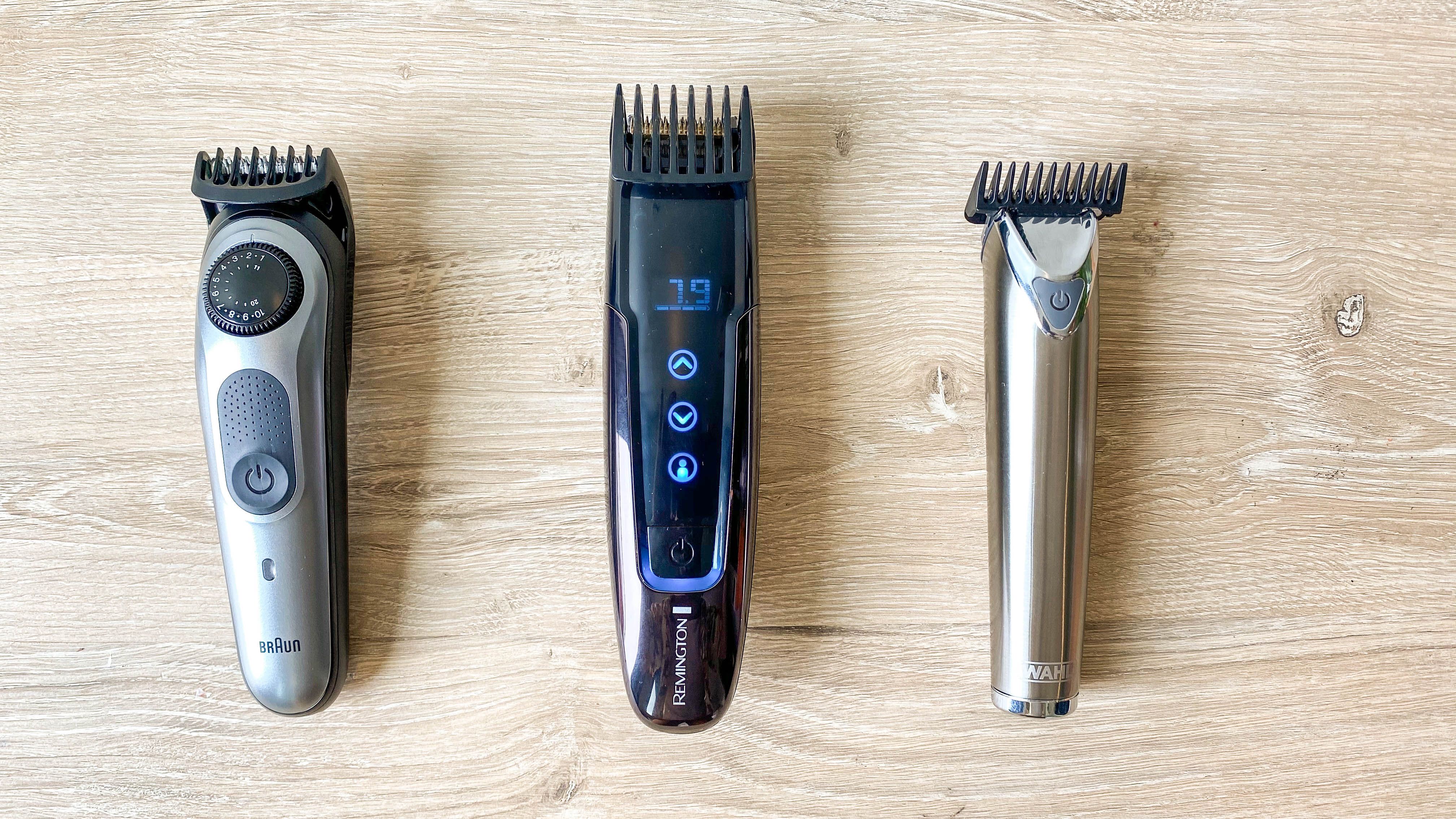 A beard trimmer with clip-on guards, small grooming scissors, and a wooden beard comb laid neatly on a bathroom countertop